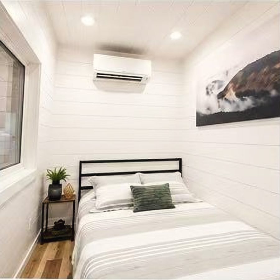 Bedroom with white shiplap walls, split air-conditioner and a double bed