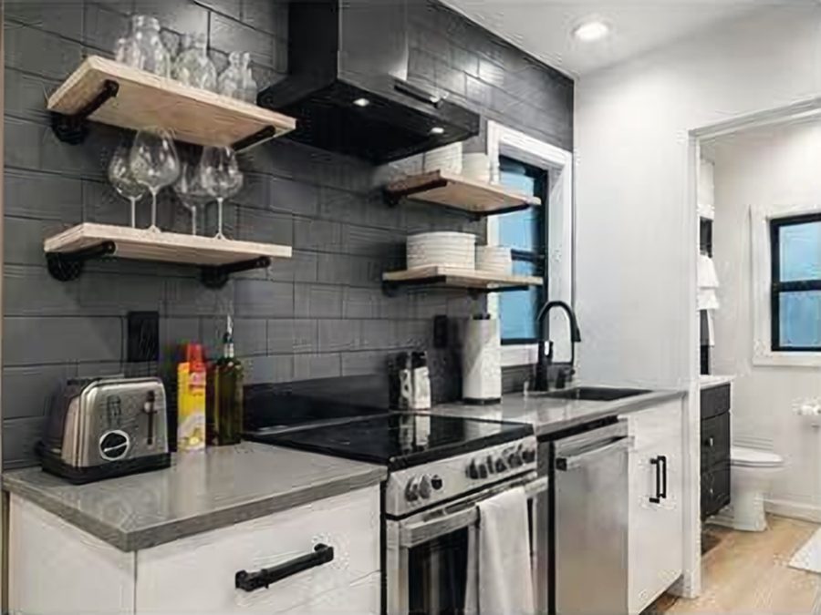 Kitchen with dark tile, open oak shelves, electric range and dishwasher