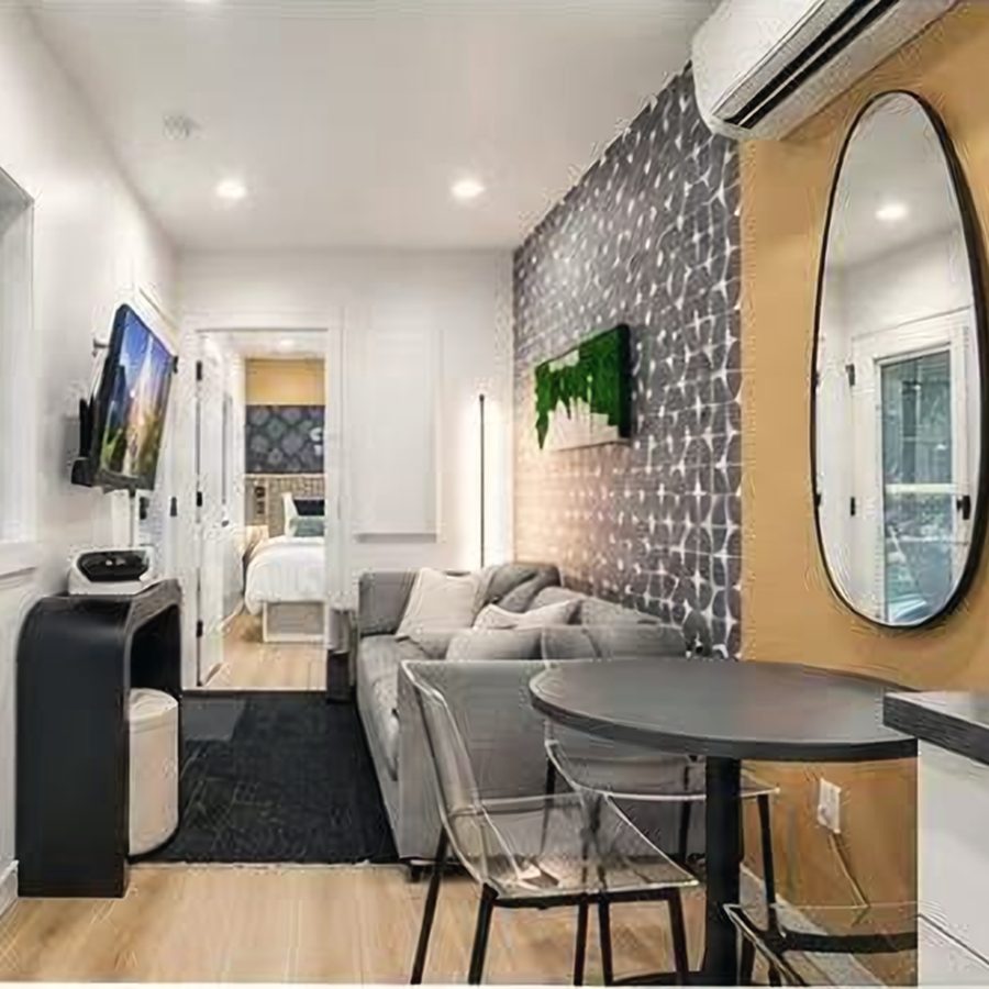 Living room with sofa, round dining table and a view through to the bedroom