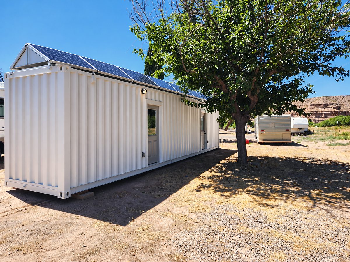 White 40 ft container office with solar panels under a shade tree